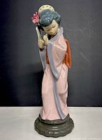 Front view of the 12-inch tall geisha figurine showing pink kimono and hand holding a fan, floral decoration in hair.