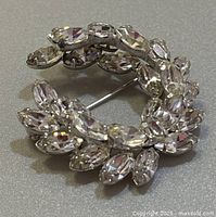 Close-up photo of front side of vintage Sherman brooch with clear rhinestones in a circular wreath pattern.