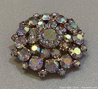 Front view of the round Sherman brooch showing clustered purple and iridescent rhinestones in gold-tone setting.