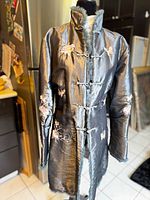Front full view of metallic silver brocade coat on mannequin, showing floral embroidery, fur-trimmed collar, and toggle closures.