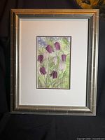 Full front view of framed floral artwork, shows metallic silver frame and white double mat with purple inner border.