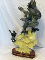 Full view of iron birds sculpture mounted on green carved hardstone base and wooden stand.
