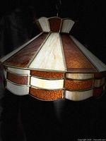 Close-up angled view of the stained glass lamp showing amber and cream glass panels with scalloped edge detail.