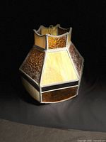 Vintage stained glass hanging lamp displayed against black background showing overall shape and glass panel colors and pattern.
