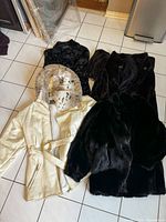 All four coats laid out on floor showing front views including cream faux leather coat with belt and three faux fur coats.