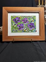 Frontal view of framed fresco painting featuring vibrant purple pansies, bees, and ladybugs on green background.