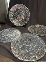 Set of four clear Vetropuro bubble glass plates displayed on black background, showing round plates with textured bubble pattern.
