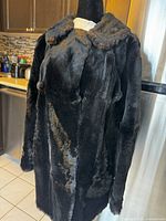 Front view of vintage black fur coat on mannequin, showing plush collar and front button detail.