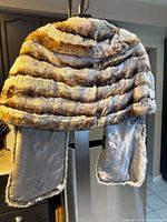 Full view of vintage chinchilla fur stole showing the natural color bands and satin lining with floral patterns.