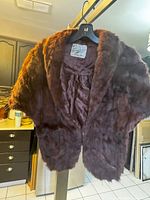 Photo of front side of brown mink stole hanging, showing dense soft fur and classic shrug style with original label.