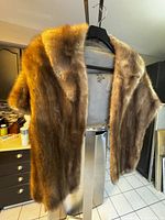 Front view of vintage muskrat fur stole showcasing soft, dense fur in warm brown with satin lining visible inside.