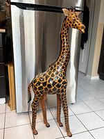 Full front-side view of the giraffe sculpture showing its height, posture, and detailed hand-painted spots on leather.