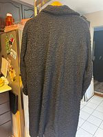 Full back view of the black Persian lamb coat showing textured curly wool finish.