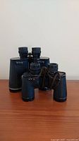 Two pairs of black vintage binoculars, first photo showing both items front side.