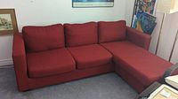 Front view of the red L-shaped couch showing cushions and armrests.