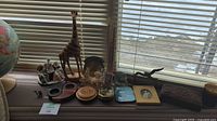 Overview of multiple decorative items including globe, giraffe sculpture, elephant figurine, and assorted trays.