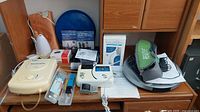 Overview of health and wellness items showing heating pad, BreathSlim respiratory trainer, pulse oximeter, blood pressure monitor, circulation booster and other devices.