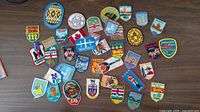 Top-down view of entire patch collection spread on table, showing various Canadian travel and provincial patches.