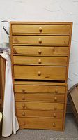 Photo of two wooden storage drawer units stacked together showing natural wood grain and several drawers with wooden knobs.
