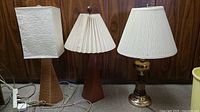 Image showing three ceramic base table lamps with four lampshades: one wrapped in jute twine, one cream accordion shade, one ribbed fabric shade, plus one brass colored metal base lamp.