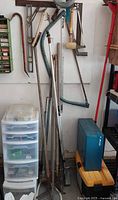 Wide view showing hanging hand tools and storage units including blue toolbox and white drawers