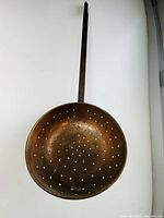 Front view, showing full ladle with copper bowl and long iron handle against white background.