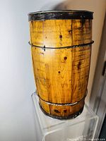 Side view of the antique wooden nail keg barrel showing wood finish and metal rims