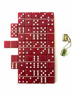 Set of 28 red bakelite dominoes arranged face up, showing the dots clearly, alongside two small bakelite dice keychains in brass cages on a white background.
