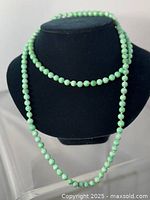 Front view of the green stone beaded necklace displayed on a black bust form, showing the full length and clarity of beads.