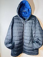 Full front view of the black Michael Kors men's winter jacket with hood hung on hanger.