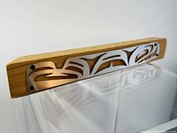 Artwork resting on a clear acrylic stand, showing the metal inlay attached on the light wooden base, angled to reveal texture and detail on metal and wood.