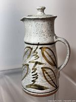 Side view of Robin Hopper mid-century modern water jug with hand-painted olive leaf design under speckled off-white glaze.