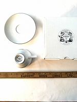 Top view of a white porcelain tea saucer, tea cup bottom with Mariage Freres logo, and original box showing Mariage Freres logo sticker. Wooden ruler measuring the cup shows scale.