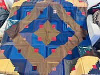 Full view of the Southwest style patchwork quilt blanket laid flat, showing the large geometric diamond pattern in blue, brown, and red fabric strips.
