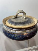 Close-up side view of vintage Jack Herman pottery casserole pot with lid showing glaze and handle details.