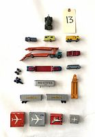 Top view of vintage metal toy vehicles, varied models including cars, camper, tank, trailers, and small binocular toy.