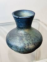 Photo showing vintage Raku pottery vase with bulbous body and narrow neck, featuring blue and purple glaze.