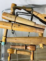 Overhead shot of seven vintage wooden beer barrel taps and spouts arranged on clear surface showing varied shapes and metal components.