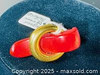 Photo of the front side of the brooch showing the gold tone circle element and red enamel detail on a blue velvet background.