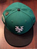 Front and top view of green and black New York Mets baseball cap with white logo.