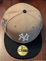 Front view of beige New York Yankees baseball cap with black brim and white embroidered NY logo, showing 59FIFTY size sticker on brim.