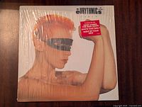 Front cover of the Eurythmics 'Touch' vinyl record showing a person with bright orange hair and a black blindfold, still sealed in shrink wrap.