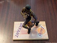 Front view of Kobe Bryant figure dribbling basketball on base with his name and Lakers logo.
