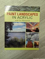 Front cover of the book shows title, author name, and example landscape paintings in acrylic including trees, water, and sunset scenes.