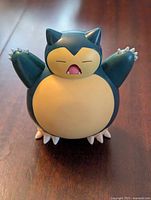 Front view of the Snorlax figure showing face, belly, outstretched arms, and claws.