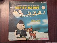 Front cover of the Rudolph the Red Nosed Reindeer vinyl record album showing illustration of Rudolph and a snowman character with text