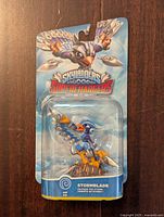 Front view of Skylanders Stormblade figure in sealed packaging, showing character on glider and Skylanders SuperChargers branding.