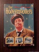 Front cover of The Honeymooners DVD box featuring Jackie Gleason and scenes from the TV show.