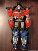 Front view of the Transformer Prime Beast Hunters Optimus Prime figure in robot mode showing the red, blue, gray colors and mounted circular weapon.