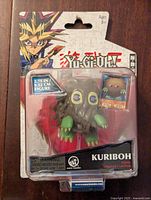 Front view of unopened Yu-Gi-Oh Kuriboh figure showing figure inside clear plastic packaging with attached collectible card sticker and Yugi character art on the card backing.
